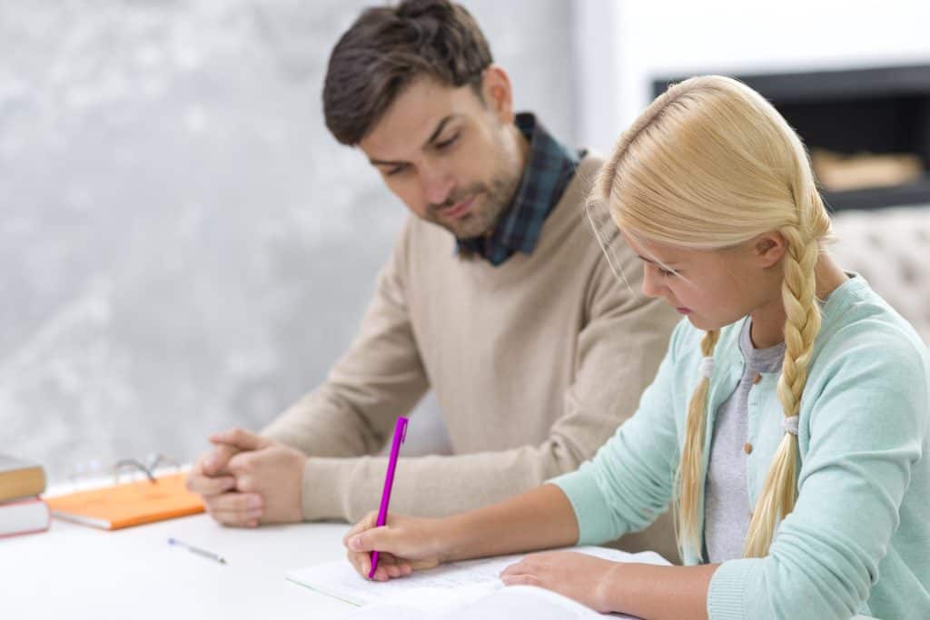Tutor helping a primary school student with written work